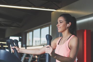 Sportif genç kadın spor egzersizleri üzerinde elektrik antrenör yapar.
