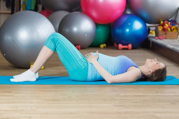 Mujer embarazada hace ejercicio en la estera — Foto de Stock