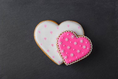 Farklı desenlerle şekillendirilmiş pembe kurabiye kalbi, siyah taş zemin