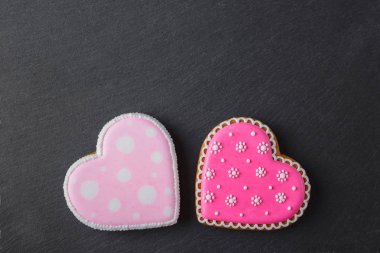 Farklı desenlerle şekillendirilmiş pembe kurabiye kalbi, siyah taş zemin