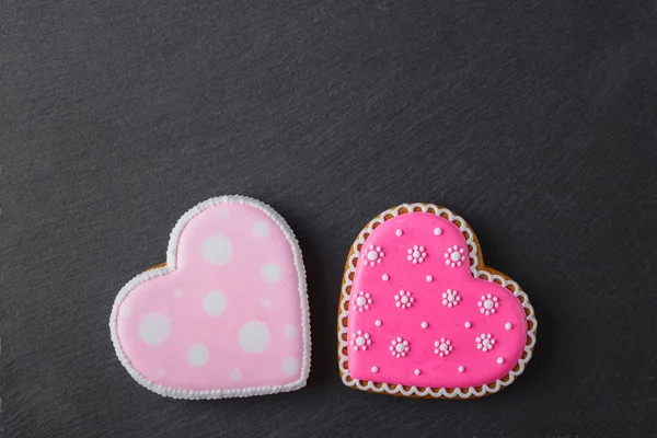 Corazón de galleta rosa en forma de con diferentes patrones, fondo de piedra de pizarra negro — Foto de Stock