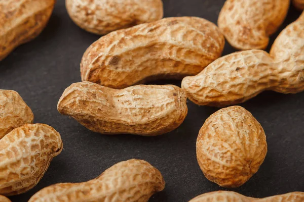 Peanuts in the shells on the black slate stone — Stock Photo, Image