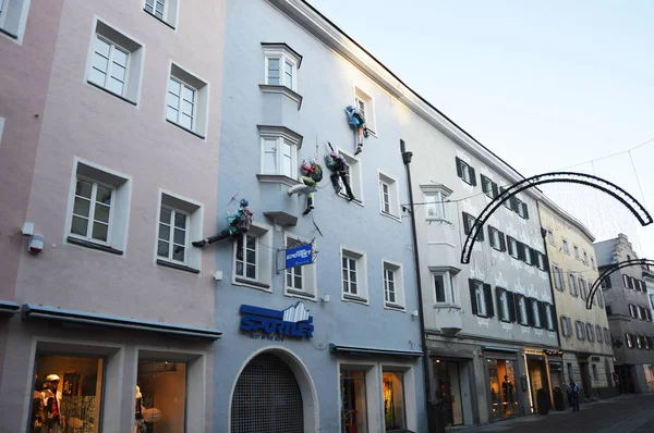 Brunico, Italia - 25 de diciembre de 2015: Curioso escalador de fachadas frente a una casa como tienda de publicidad en la zona de peatones de Bruneck, Bruneck, Italia — Foto de Stock
