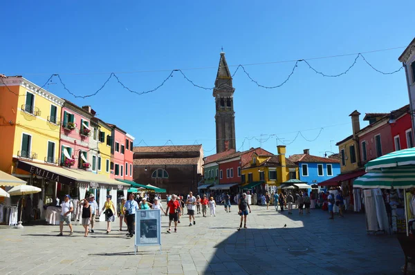 Βενετίας Μπουράνο τετράγωνο με τους τουρίστες, κλίνοντας το campanile πύργο κουδουνιών και τυπικό πολύχρωμα σπίτια στο κάτω μέρος, Βενετία, Ιταλία καλοκαίρι 2016 — Φωτογραφία Αρχείου