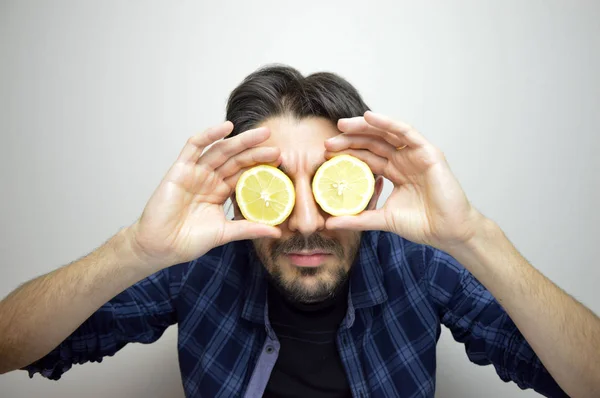 Een nieuwsgierige jonge man voor zijn ogen met citroenen ontdekken een nieuw ding / nieuw product — Stockfoto