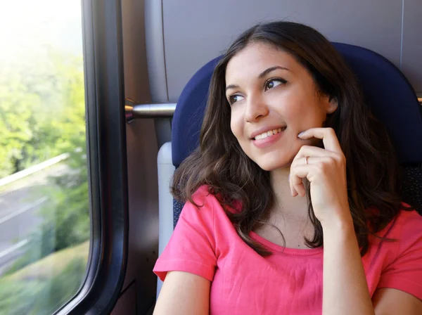 Young beautiful woman looking through the train window. Happy train passenger traveling sitting in a seat and looking through the window. Modern people city lifestyle. Young urban woman. — Stock Photo, Image