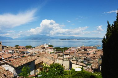 Bir Desenzano Del Garda, İtalya - 15 Mayıs 2017: panorama eski şehir çatılar, dağlar, beyaz bulutlar ve yelkenli gölde, Desenzano del Garda, İtalya ile Desenzano Kalesi: Garda Gölü üzerinde şaşırtıcı