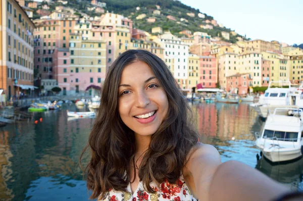 Joyeux jeune femme bronzée prenant selfie photo dans un paysage typiquement italien avec des maisons portuaires et colorées pour des vacances italiennes en Ligurie, Italie — Photo