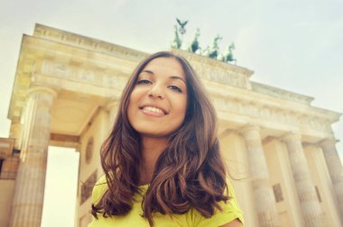 Brandenburg Kapısı, Berlin, Almanya önünde mutlu gülümseyen kız. Güzel ve genç birbayan seyahat Avrupa'da.