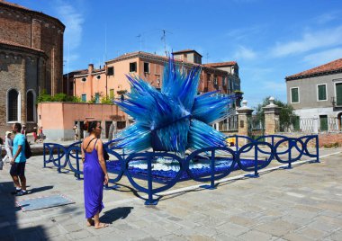 Murano, İtalya - 9 Ağustos 2016: kimliği belirsiz bir kadın ile mavi elbise ve ünlü mavi cam heykel göstermek tarafından Simone Cenedes Murano Adası bulunan Venedik Laguna, Murano, Venedik, İtalya