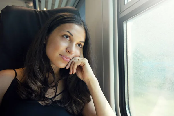 Mladá krásná žena při pohledu z okna vlaku. Happy vlak osoba cestující sedící v sedačce a dívat se skrz okno. — Stock fotografie