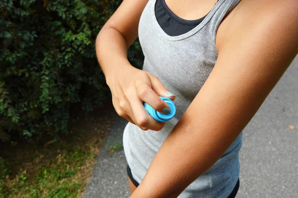 Mosquito repellent spray. Woman spraying insect repellent against bug bites on arm skin outdoor in nature forest using spray bottle.