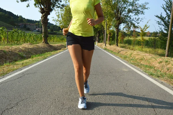 Fitness woman running on asphalt road — Stock Photo, Image
