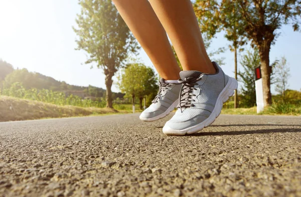 Koşu ayakkabıları atlamak. Fitness kadın rotasyon ayak hop asfalt yolda günbatımında çalıştırmak. — Stok fotoğraf