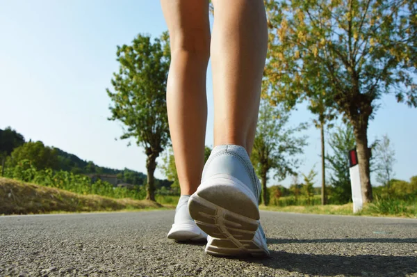 Молодая женщина фитнес ноги бежит по асфальтовой дороге — стоковое фото