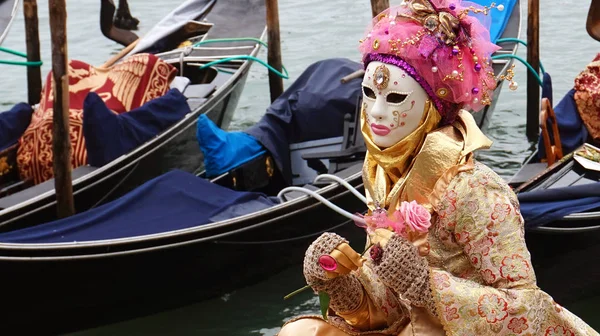 Venedig, Italien - 23. Februar 2017: ein unbekannter Maskierter im Kostüm während des venezianischen Karnevals mit Gondeln im Hintergrund — Stockfoto