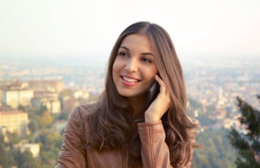 Neşeli genç bayan dışında onu telefonla konuşuyor. Cityscape backgroud tarih ile genç iş kadını.