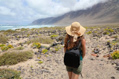 Macera seyahat kavramı. Etkileyici fantastik Lanzarote yatay olarak arayan genç kadın. Yürüyüş ve Lanzarote Adası muhteşem görüş isteyen hasır şapkalı kadın figürü arkadan görünüm. 
