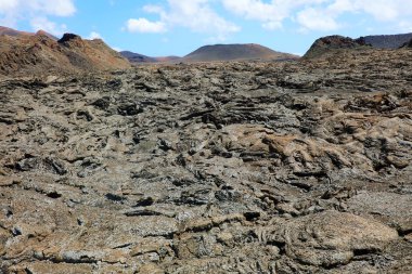 Lav akışı ve kabuk üzerinde arka planda Timanfaya Milli Parkı, Lanzarote, Kanarya Adaları volkanik dağlar ile katılaşmış