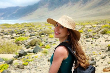Mutlu güzel traveler kızla hasır şapka kameraya bakıyor. Genç kadın backpacker Lanzarote, Kanarya Adaları keşfetmek.