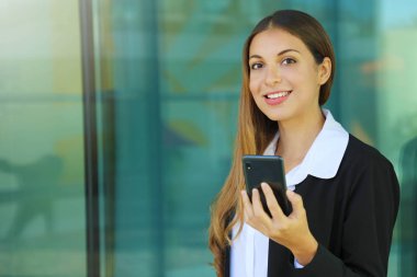 İş kadını cep telefonu tutuyor ve dışarıdaki kameraya bakıyor.
