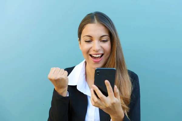 Emocionado joven gerente que recibe buenas noticias en el teléfono inteligente al aire libre contra fondo azul . —  Fotos de Stock