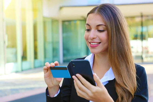 Mulher de negócios segurando telefone inteligente leitura número de cartão de crédito fazendo compras on-line escritório ao ar livre no tempo de pausa. Pessoas e pagamento on-line em todos os lugares conceito . — Fotografia de Stock