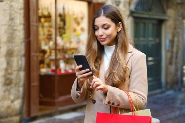 Alışveriş yapan kadın, şehirdeki akıllı telefondan internetten ürün almayı seçiyor..