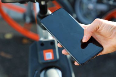 Bisikletleri paylaşırdık. Şehirde paylaşılan motorun Qr kodunu taramak için akıllı telefon kullanılıyor.