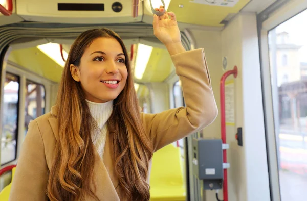 Молодая деловая женщина держит ручку при переезде в современном трамвае. Счастливый пассажир наслаждаясь поездкой с общественным транспортом . — стоковое фото