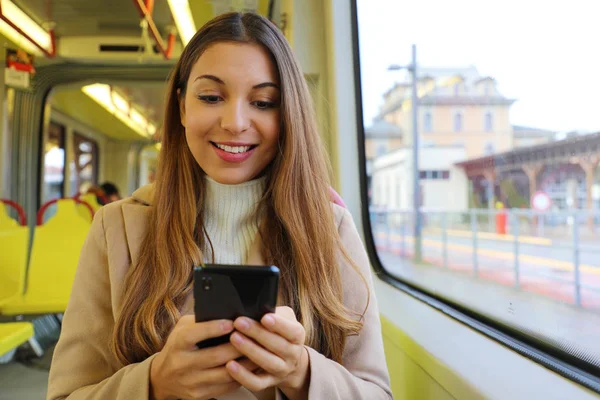 Mensajería de mujer joven con teléfono inteligente sentado en el tranvía . — Foto de Stock