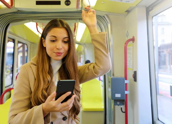 People on public transport. Young business woman reading message on her smart phone on the tram.