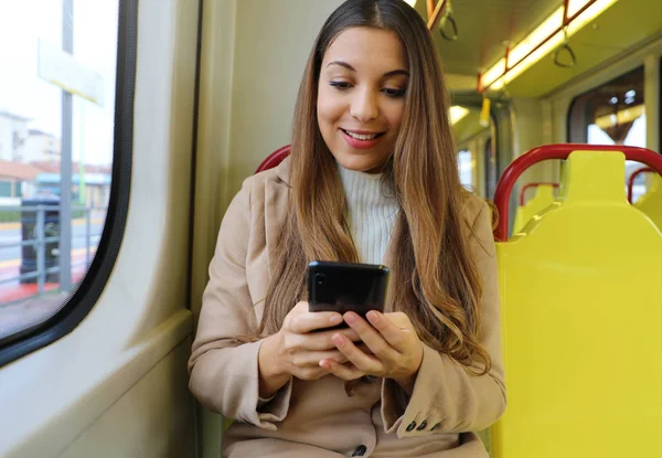 Mensajería de mujer joven con teléfono inteligente sentado en el tranvía . — Foto de Stock