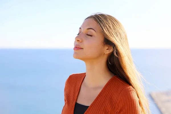 Primer plano de hermosa chica relajada respirando aire fresco con el mar azul en el fondo . — Foto de Stock