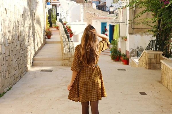 Kíváncsi fiatal nő sétál Alicante régi utcájában, Spanyolországban. Hátsó nézet a Dél-Európába látogató vidám lányról. — Stock Fotó