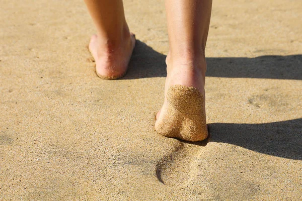 ビーチの女性の足の砂の日没の黄金の砂の上に足跡を残し裸足で歩く。夏にリラックスした休暇旅行の自由の人々. — ストック写真