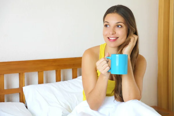 Pensive žena v posteli pití kávy nebo čaje a přemýšlel při pohledu bokem doma — Stock fotografie