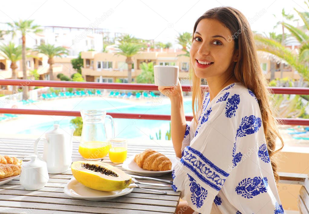 Breakfast woman eating brunch on travel in resort hotel drinking hot cappuccino coffee view from outside balcony