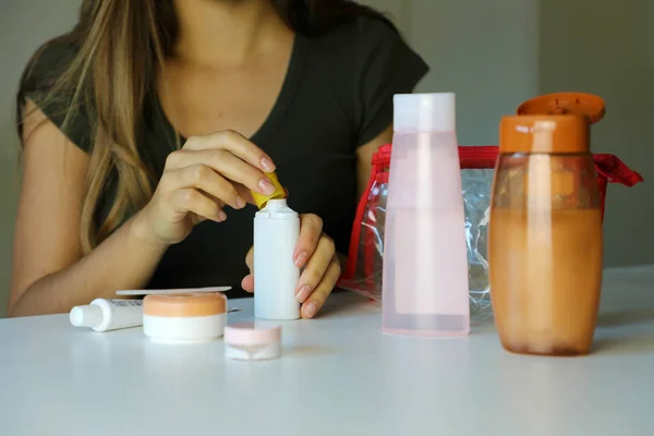 Girl poured liquid into small bottles preparing travel kit for transporting on airplane. Travel kit for transporting liquid and cosmetics on airplane concept.