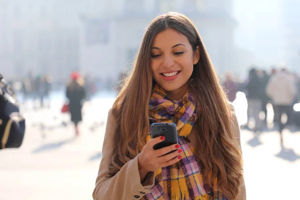Портрет красивой улыбающейся молодой женщины, переписывающейся на мобильном телефоне — стоковое фото
