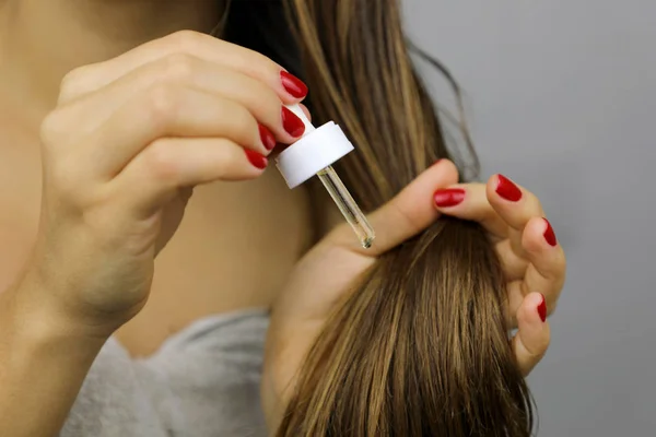 Mujer aplicando aceite sobre el cabello seco o concepto de protección solar. Dividir — Foto de Stock