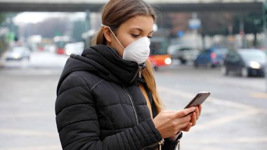 COVID-19 Salgın Coronavirus Genç Kadın Şehir Caddesinde Akıllı Telefon Kullanıyor. Covid-19, Hava Kirliliği, Partiküller, Grip Virüsü ya da Grip Hastalığı Yüzü Yüzü Yüzü Yüzünde