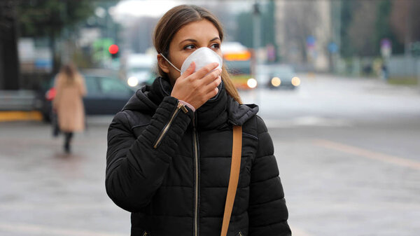 COVID-19 Pandemic Coronavirus Woman in city street wearing face mask protective for spreading of disease virus SARS-CoV-2. Girl with protective mask on face against Coronavirus Disease 2019.