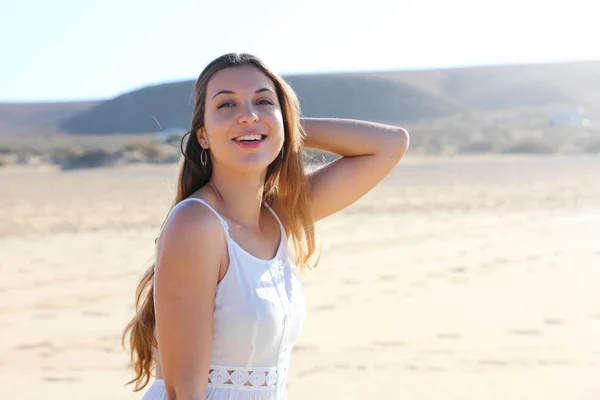 Досить розслаблена молода жінка посміхається на камеру ходить на пляжі — стокове фото