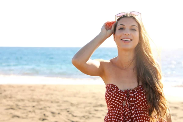 Belleza mujer bronceada de moda con gafas de sol en la cabeza en la playa mirando a la cámara — Foto de Stock