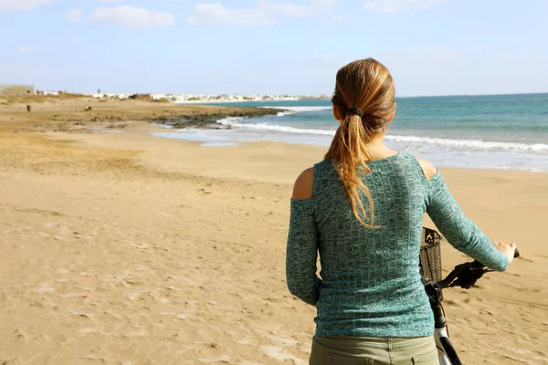 Baksidan visa kvinna promenader med cykel längs stranden sand livsstil bekymmersfri — Stockfoto