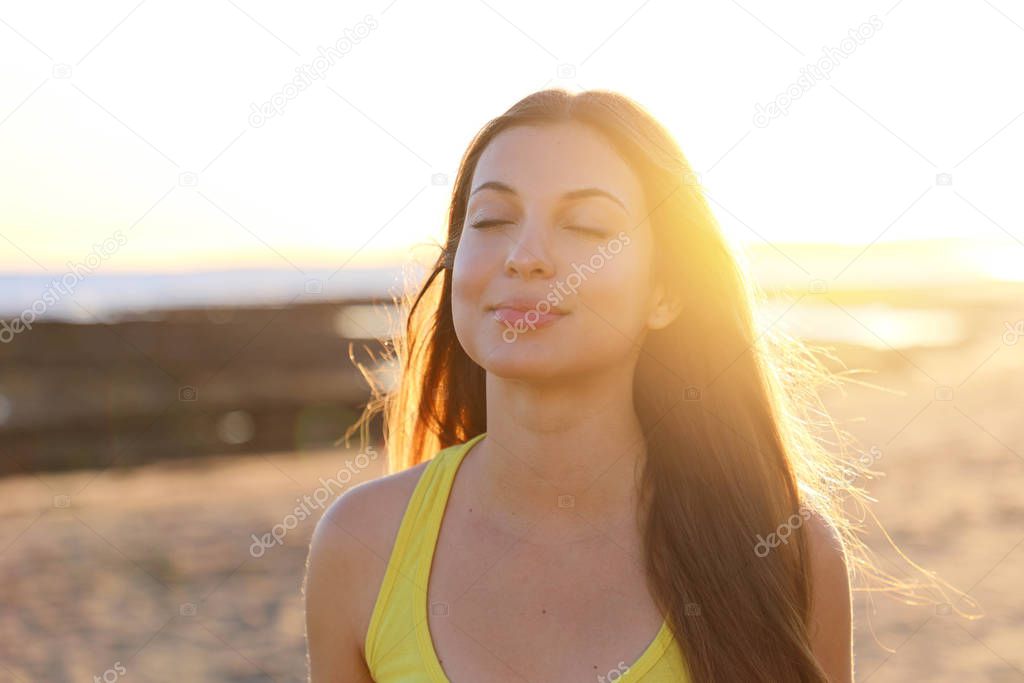 Backlight portrait of a woman breathing deep fresh air in the morning sunrise on the beach