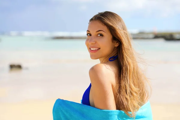 Feliz sorrindo jovem mulher coberta de toalha azul relaxado na praia olhando para a câmera. Férias de verão conceito . — Fotografia de Stock