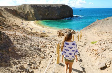 Lanzarote 'de tatil. Genç ve güzel bir kadının arka görüntüsü Playa Papagayo, Lanzarote, Kanarya Adaları 'na kadar uzanır..