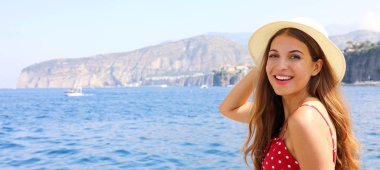 İtalya 'da yaz tatili. Panoramik pankartta Sorrento sahili, İtalya 'da şapkasını tutan genç bir kadın görülüyor..